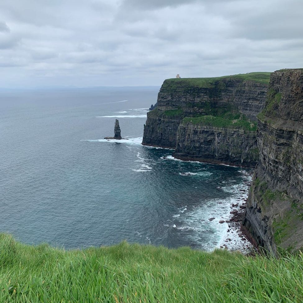 mountain beside the ocean under gloomy sky